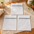 Nest Mesh Laundry Bag Trio hero: Three Nest white mesh laundry bags with grey zips