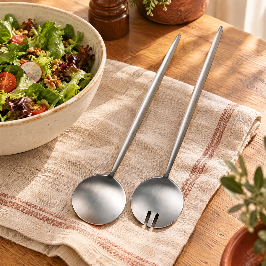 Salad serving pair beside a shared leafy salad